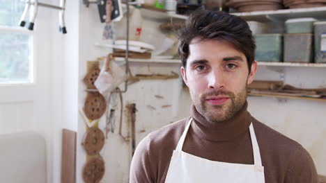 retrato de un alfarero sonriente con un delantal en un estudio de cerámica