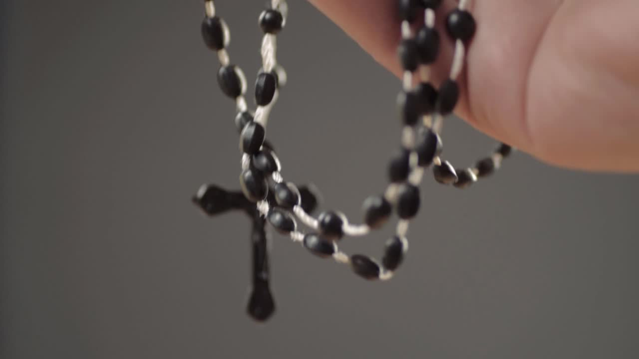 Hands holding string of rosary beads close up