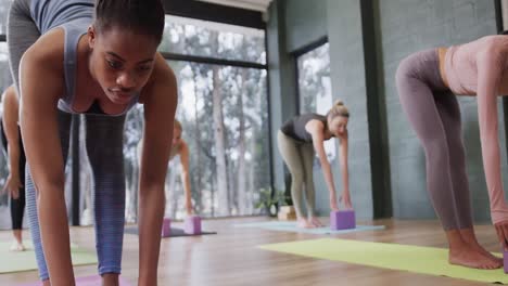 Fokussierte,-Vielfältige-Frauen,-Die-Sich-Gemeinsam-Auf-Matten-Im-Yoga-Kurs-Mit-Einer-Trainerin-Dehnen,-Zeitlupe