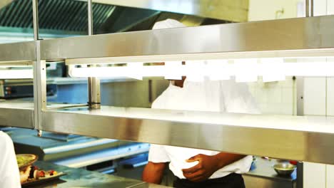 Chef-handing-food-dish-to-waitress-at-order-station