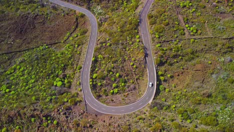 bird's eye aerial view of sharp road turn with white car vehicle passing by