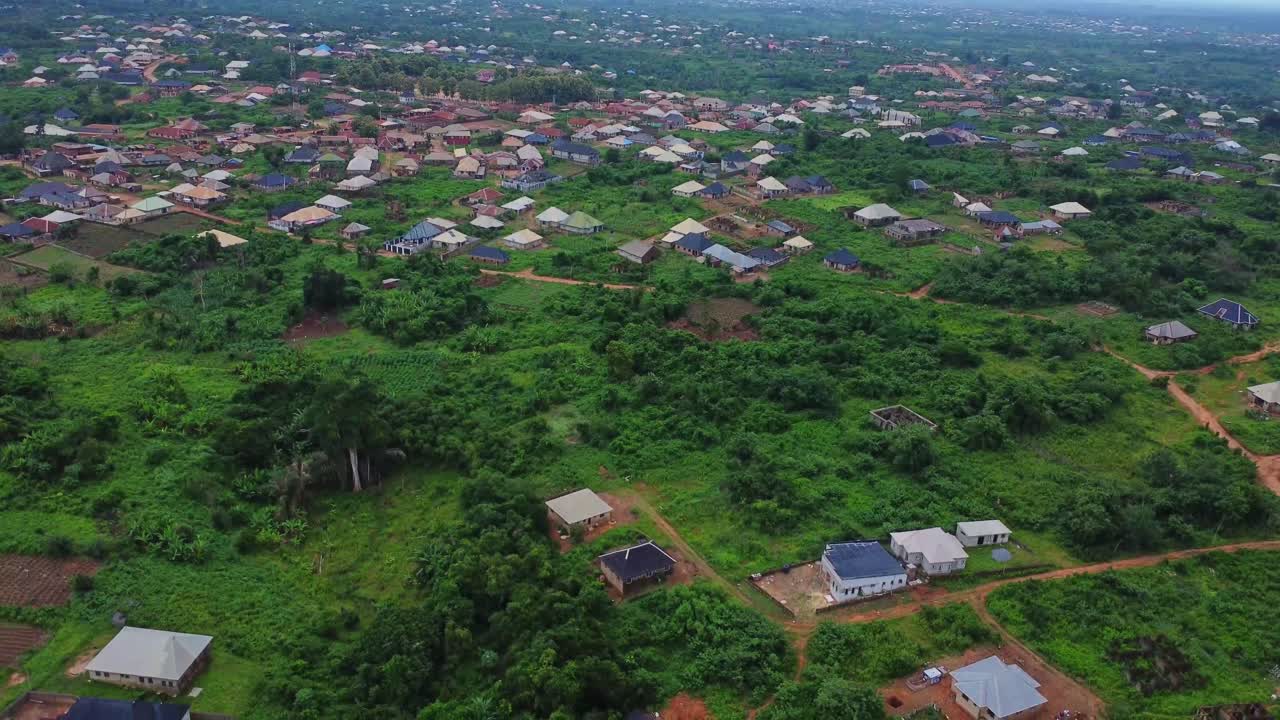 Jib down of a large farming town surrounded by green nature in Nigeria, Africa