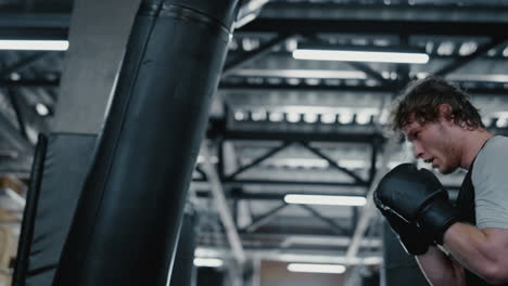 anxious fighter hitting punching bag at gym. kickboxer working on blows