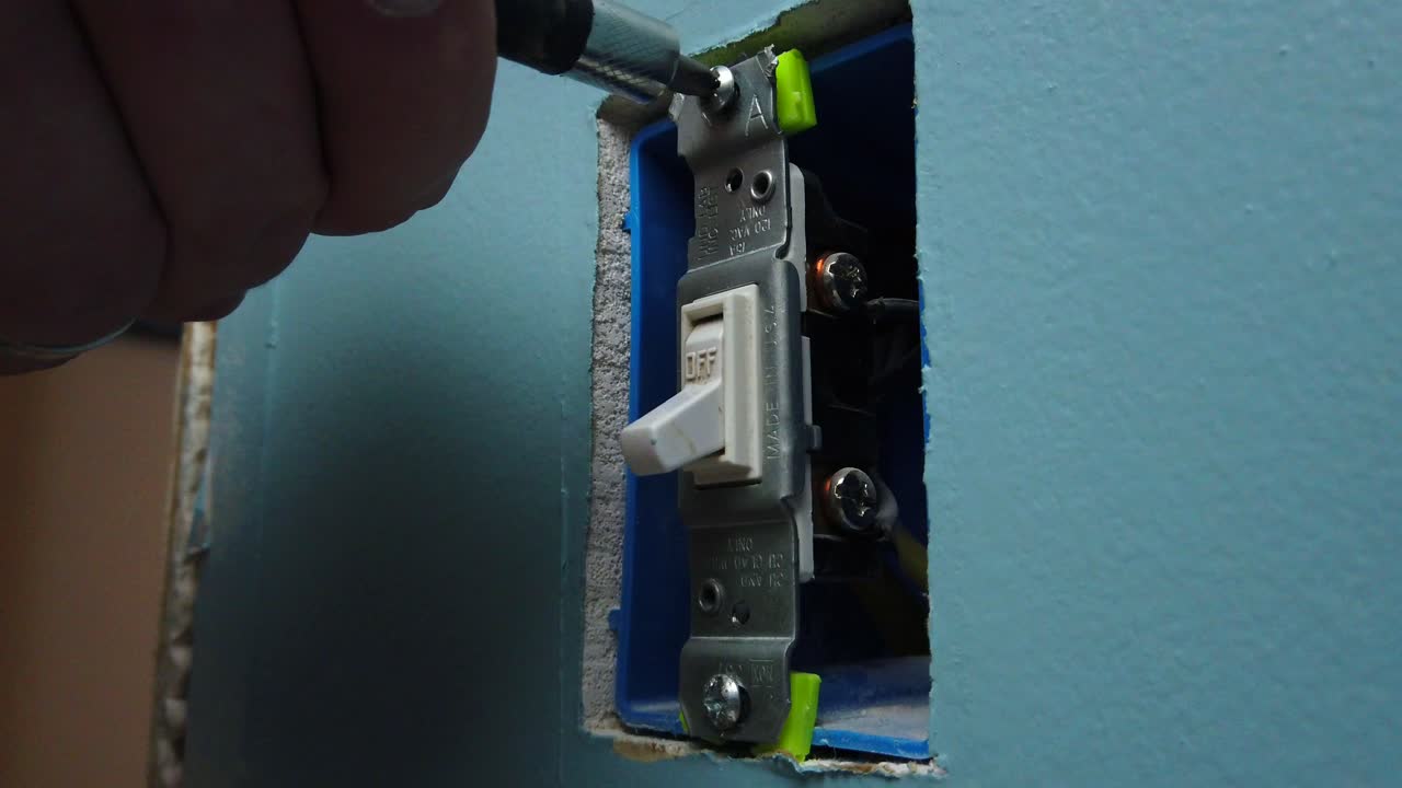 Unscrewing an old light switch from a box in the wall