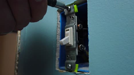 desenroscando un viejo interruptor de luz de una caja en la pared