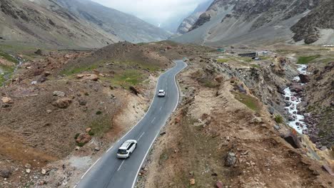 Aerial drone shot showcasing cars driving along serpentine roads carved into the mountainside.