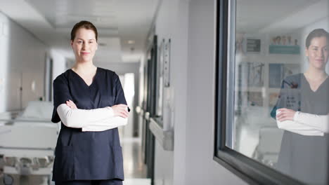 portrait of happy caucasian female doctor wearing scrubs in hospital, copy space, slow motion