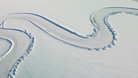 part of a race track on a frozen lake in finland during golden hour – aerial winter landscape top down