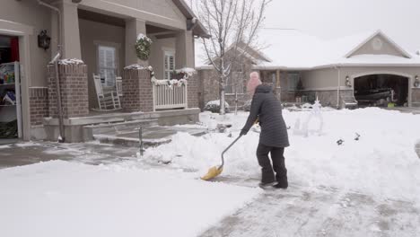 senior woman shoveling snow from her driveway