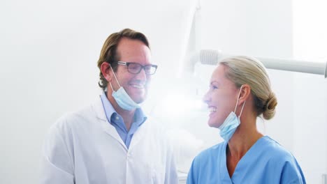 Smiling-dentist-talking-to-dental-assistant