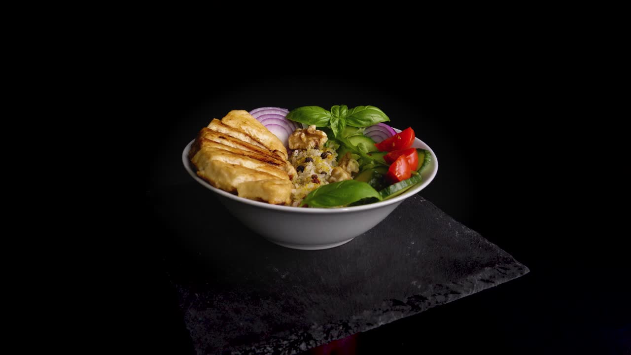 슬레이트 접시에 자른 신선한 양파, 토마토, 오이, 밥 위에 바질 장식을 곁들인 회전하는 채식 고기 그릇에 천천히 돌리