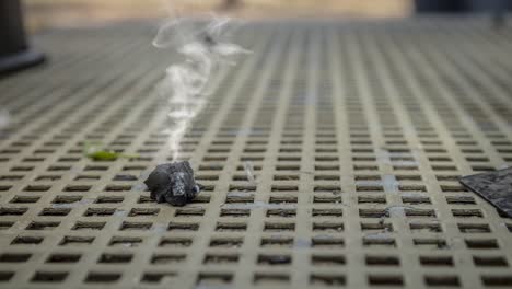 cinemagraph of smoke emitted from a piece of burnt wood coal on a metal table