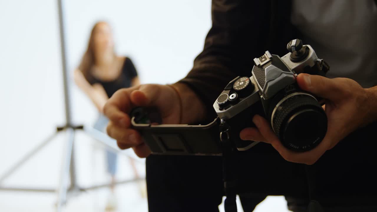 fotógrafo de sexo masculino poniendo el rollo de película en la cámara 4k