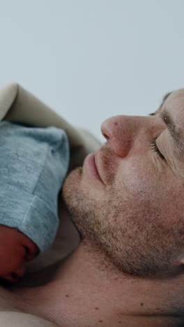 caucasian dad is happy to hold his just born child. the baby is put on father's chest for skin to skin contact. vertical video