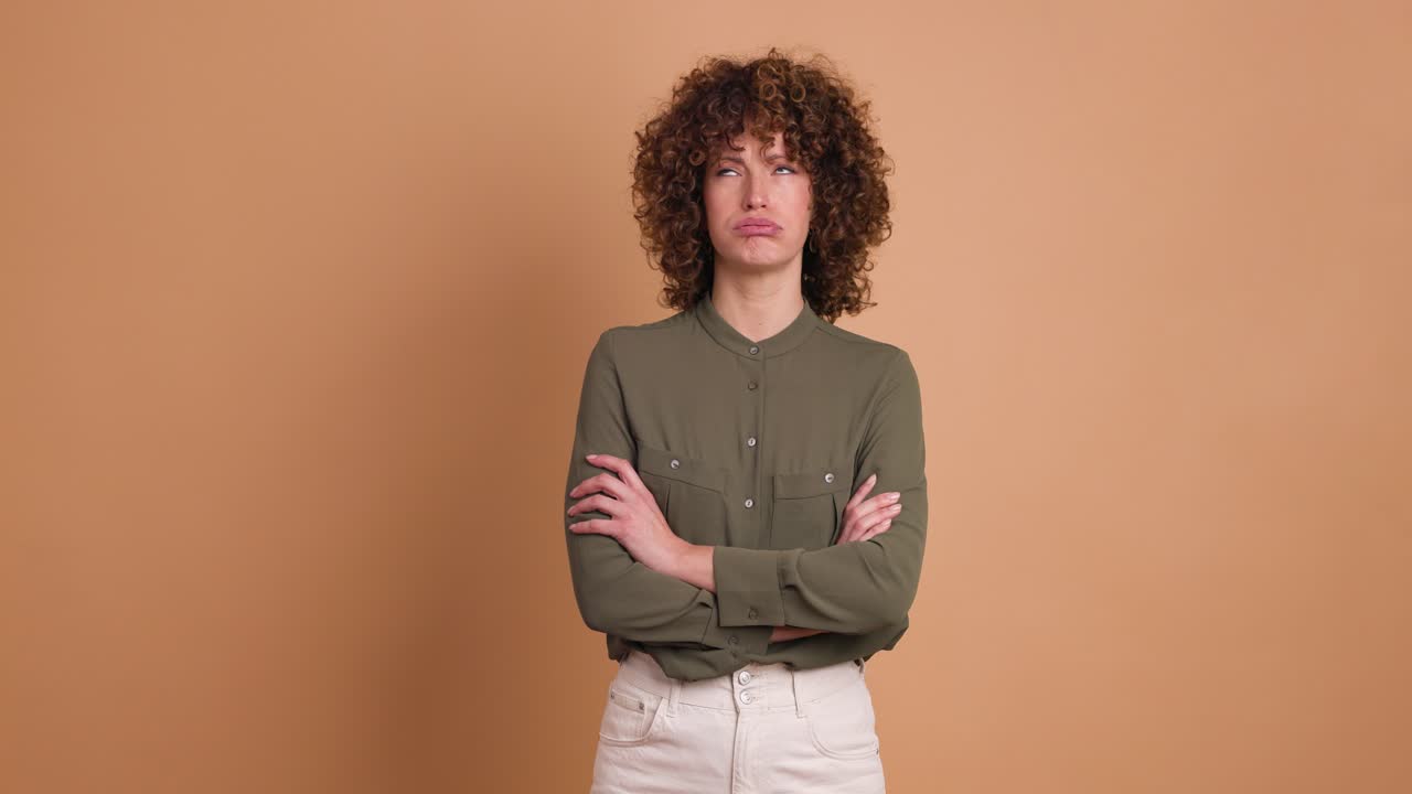 Disagreeing young woman shaking head with twisted mouth on beige background
