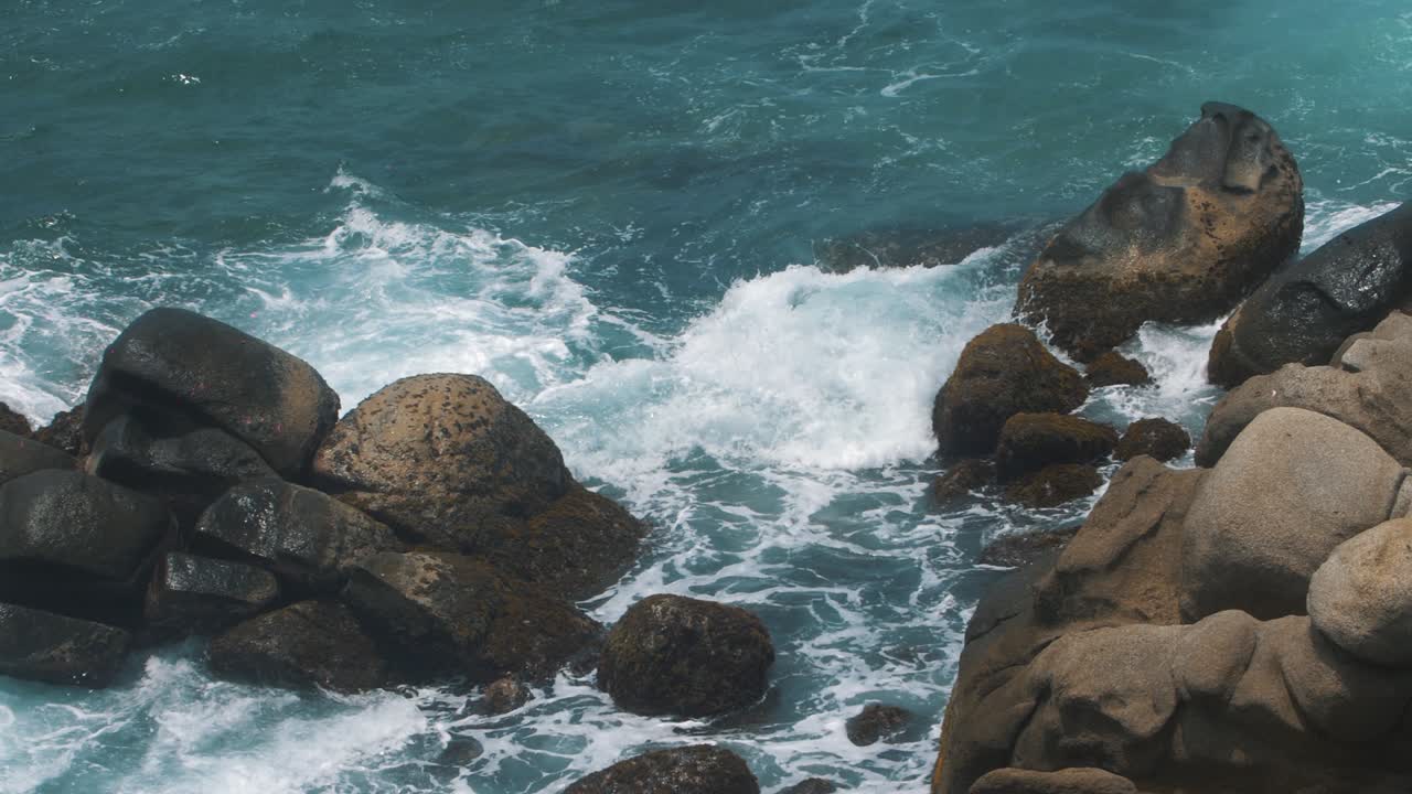 Bella ripresa al rallentatore di onde che si infrangono contro gli scogli sulla spiaggia del Parco Tayrona, Colombia