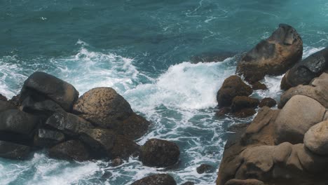 Hermosa-Toma-En-Cámara-Lenta-De-Olas-Rompiendo-Contra-Las-Rocas-En-La-Playa-Del-Parque-Tayrona,-Colombia