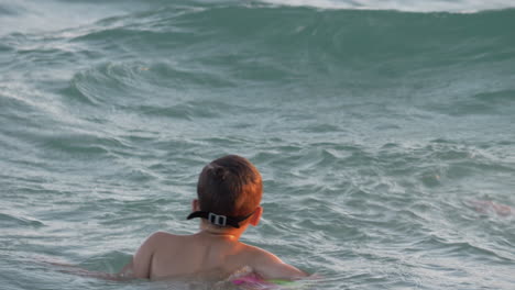 child is happy to swim on sea waves