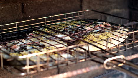 open fire barbecue with blackfish on grid being grilled, closeup