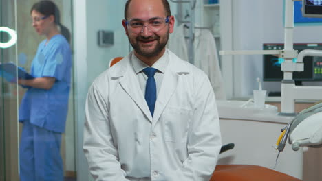 Stomatologist-smiling-at-camera-sitting-in-dental-office