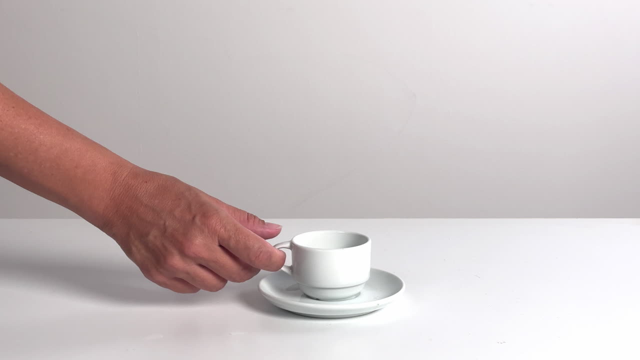 Mano che prende e appoggia una tazza di caffè bianca