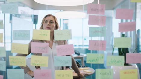 beautiful-business-woman-using-sticky-notes-brainstorming-ideas-planning-strategy-problem-solving-with-creative-mind-map-working-on-solution-in-office-4k