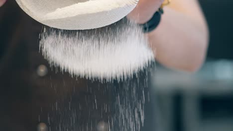 confectioner strains white flour through fine sieve