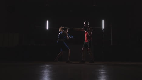 woman punches the focus mitts in the boxing gym