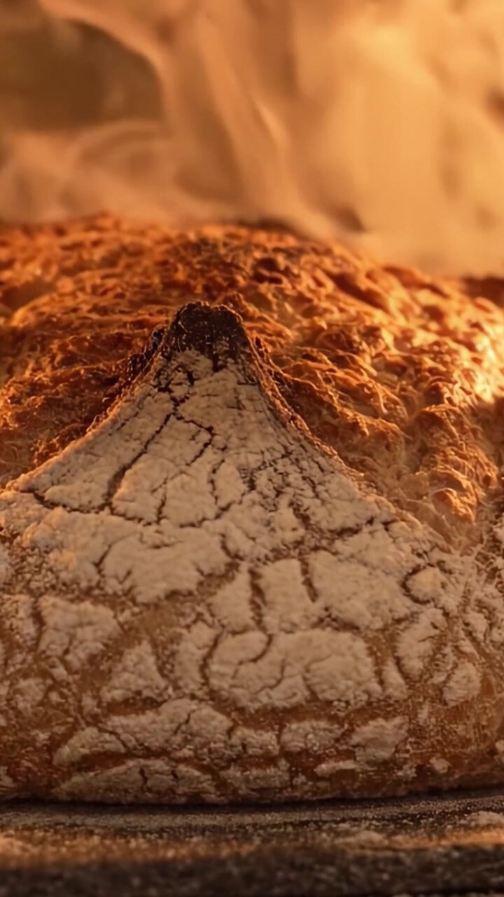 Golden Brown Artisan Bread Emerging from the Oven, Surrounded by Warm Steam, Showcasing Its Unique Crust Texture and Perfectly baked Shape