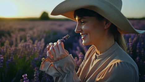 woman enjoying the fragrance of lavender in a field at sunset