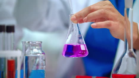 científico de laboratorio vertiendo líquido en un frasco de laboratorio. científico haciendo un experimento de laboratorio