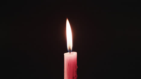 video of red candle with white flame and copy space on black background