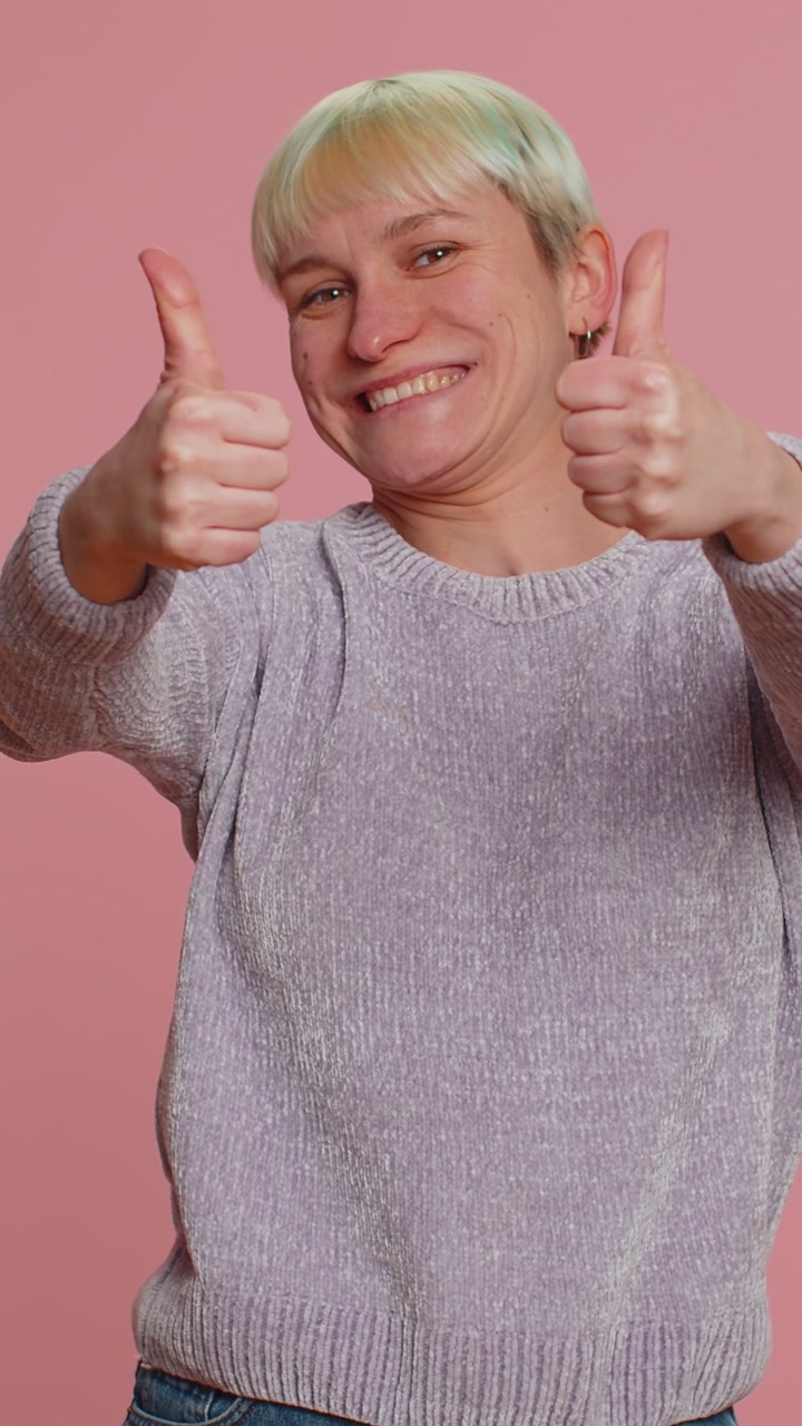 Hipster woman raises thumbs up agrees or gives positive reply recommends advertisement likes good
