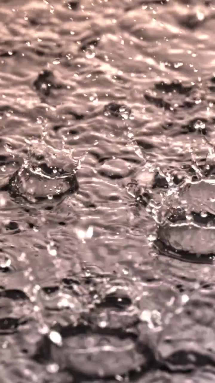 Nahaufnahme: Regentropfen spritzen auf Wasseroberfläche