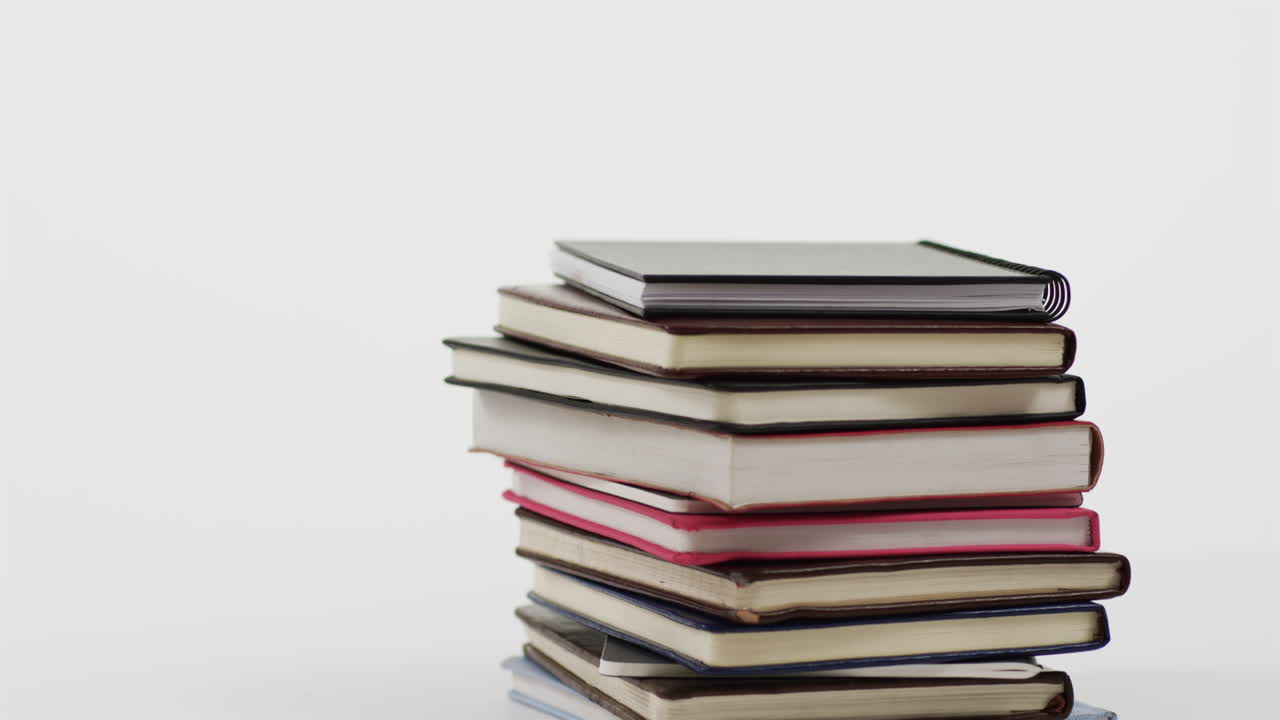 Close up of stack of books on grey background, in slow motion