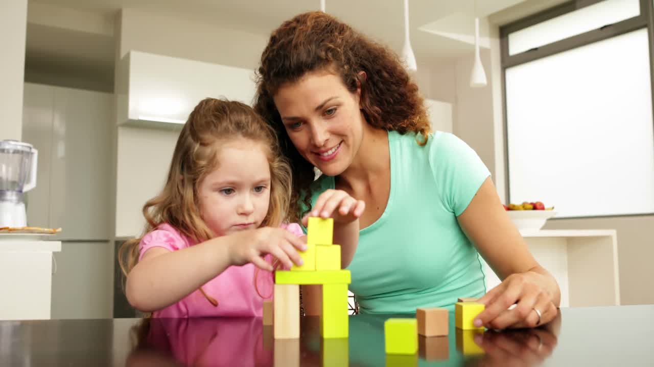 madre e hija jugando con bloques de construcción en la mesa
