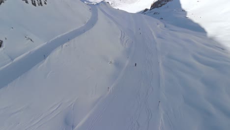 aerial drone view following downhill skiing on the slopes of the sunny alps