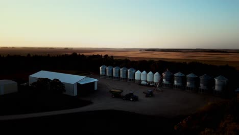 a farmer drives tractor combine completes farming into storage during as sunset night falls at the end of harvest time on a small town farm