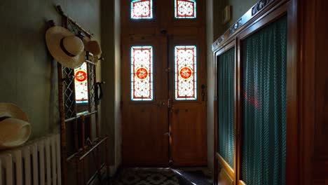 slow dolly shot of a stained glass villa door with a wardrobe and hat stand