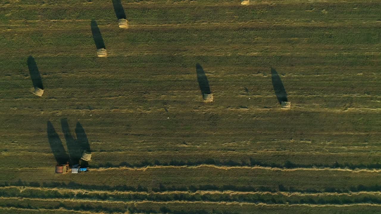 공중에서 위로 보이는 트랙터와 발링 기계가 농경지에서 실레이지 발레를 만들고 있습니다.