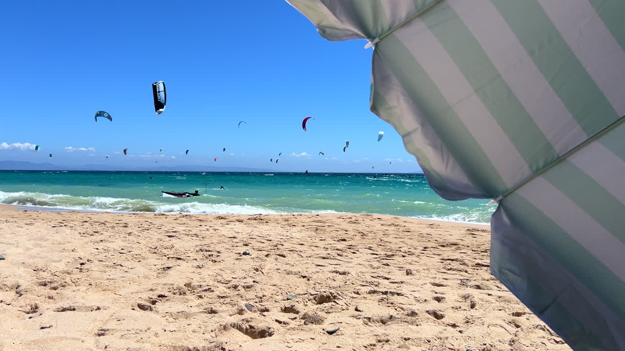 Perfect windy summer day with many kite surfers in the ocean in Tarifa Spain, fun sunny day at the beach, 4K shot