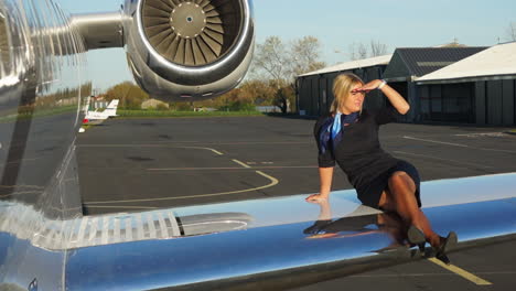 a playful flight attendant sits on the wing of an aircraft