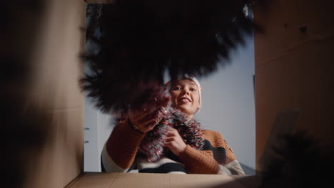 feestelijke vrouw die kerstversieringen uit de doos haalt