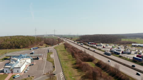 Fly-across-busy-multilane-highway.-Aerial-view-of-cars-and-trucks-driving-on-straight-motorway.-Traffic-and-transportation-concept.