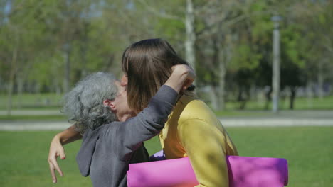 vista lateral de mujeres abrazándose en el parque, riendo