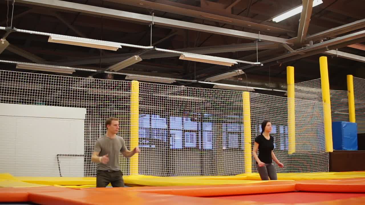 실내 시설 에서 트램폴린 에 뛰어드는 사람 들