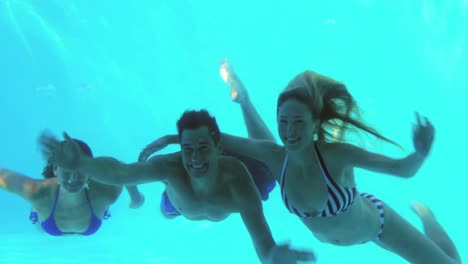 Three-friends-diving-into-swimming-pool-and-waving