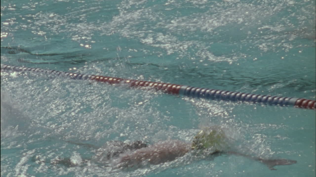 Un groupe de nageurs nagent à toute vitesse vers l'autre côté de la piscine.