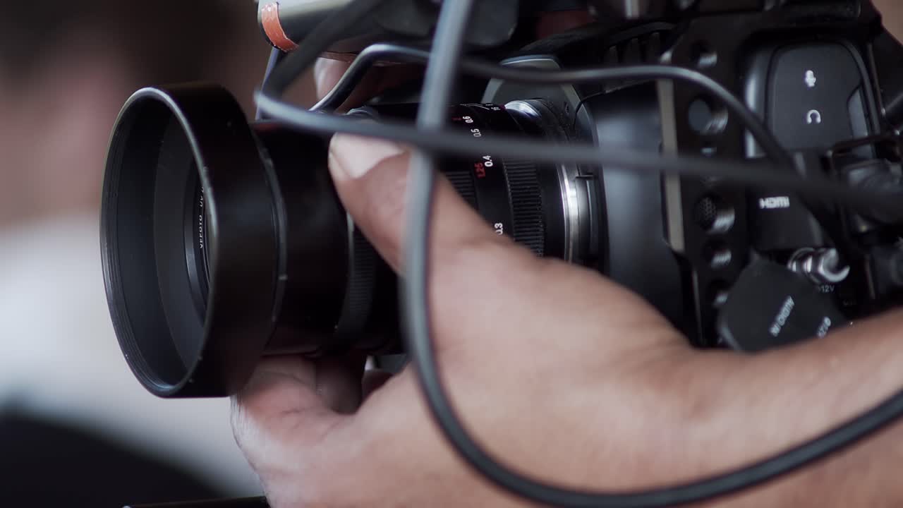 la mano del camarógrafo ajusta la apertura y la nitidez de la lente en una pequeña cámara digital