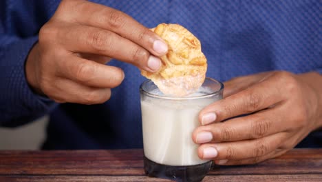 person eating cookie dipped in milk